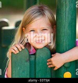 Porträt von netten blonden Mädchen festhalten an Holzzaun. Stockfoto