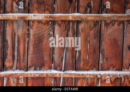 alte Scheune Wand oder Zaun mit etwas Schnee - verwitterte Holz Hintergrund Stockfoto