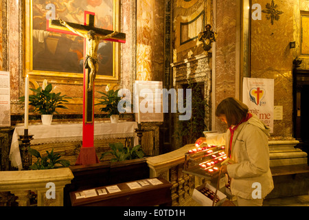 Eine Frau, eine Kerze anzünden, in die katholische Kirche von St Mary Magdalene (Santa Maria Bittermandelaroma), Rom, Italien Europa Stockfoto