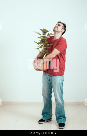 Porträt von glücklicher Mann hält der Cannabis-Pflanze und nachschlagen. Stockfoto