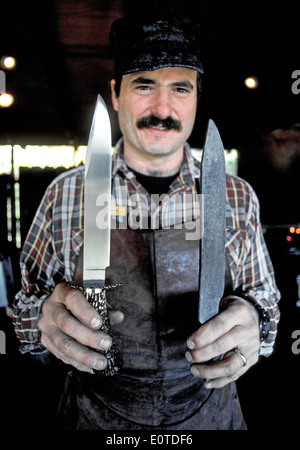 Ein Schmied zeigt die glänzenden Messer, die, das er aus rohem Metall, in seiner linken Hand an der Ozark-Folk-Center, ein State Park in Arkansas, USA geschmiedet hat Stockfoto