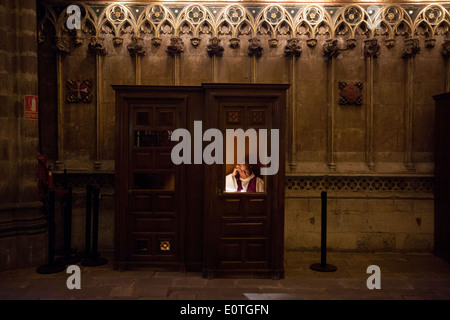 Priester warten ein Gemeindemitglied in einem konfessionellen Kasten in der Kathedrale von Barcelona Stockfoto