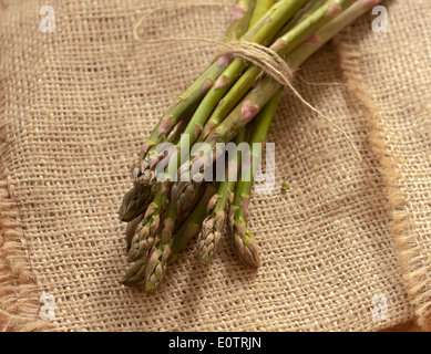 Bündel von grünem Spargel auf einem Holzbrett neben einer Leinen-Serviette Stockfoto