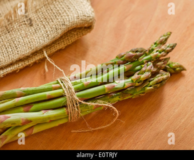 Bündel von grünem Spargel auf einem Holzbrett neben einer Leinen-Serviette Stockfoto