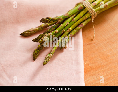 Bündel von grünem Spargel auf einem Holzbrett neben einer Leinen-Serviette Stockfoto