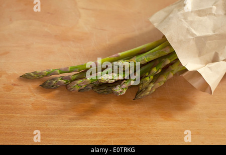 Bündel von grünem Spargel auf einem Holzbrett neben einer Leinen-Serviette Stockfoto