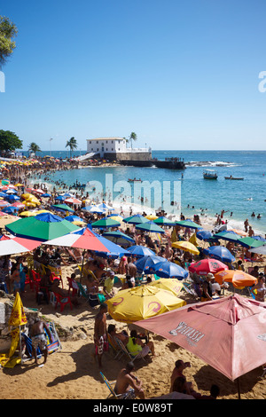 SALVADOR, Brasilien - 13. Oktober 2013: Brasilianer mit bunten Sonnenschirmen am hellen Nachmittag Porto da Barra Strand entspannen. Stockfoto