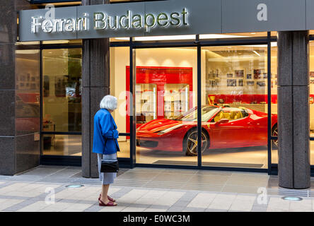 Ältere Frau stand vor dem Schaufenster von einem Ferrari-Vertragshändler, Budapest, Ungarn Stockfoto