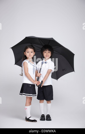 ein Junge und ein Mädchen stehen unter einem Regenschirm Stockfoto