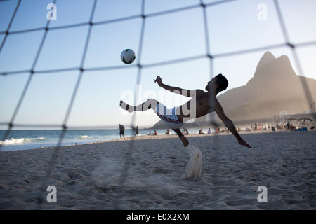 Ein Fußballer erzielt akrobatisch ein Tor aus einem Bicyclette Overhead Fußball Kick am Strand von Ipanema in Rio De Janeiro, Brasilien Stockfoto
