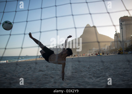 Ein Fußballer erzielt akrobatisch ein Tor aus einem Bicyclette Overhead Fußball Kick am Strand von Ipanema in Rio De Janeiro, Brasilien Stockfoto