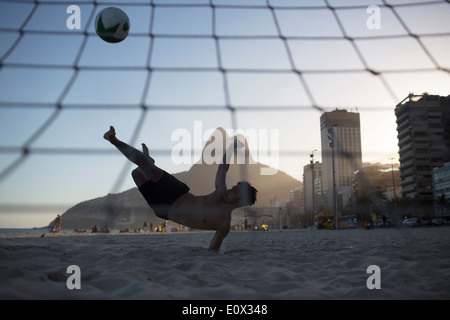 Ein Fußballer erzielt akrobatisch ein Tor aus einem Bicyclette Overhead Fußball Kick am Strand von Ipanema in Rio De Janeiro, Brasilien Stockfoto