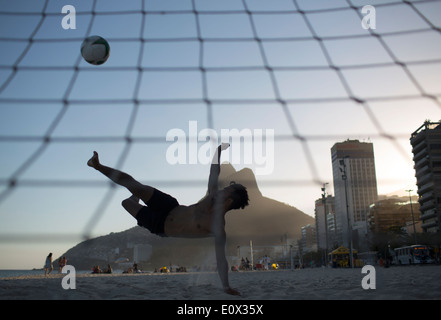 Ein Fußballer erzielt akrobatisch ein Tor aus einem Bicyclette Overhead Fußball Kick am Strand von Ipanema in Rio De Janeiro, Brasilien Stockfoto