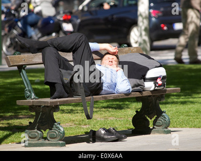 Geschäftsreisende, die zum Entspannen in der Sonne auf einer Bank im Park in Brüssel, Belgien Stockfoto