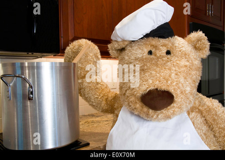 Überdimensionierte Teddybär gekleidet in Schürze und Hut des Küchenchefs in der Küche. Stockfoto