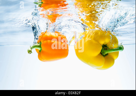 zwei gelbe Paprika ins Wasser fallen Stockfoto