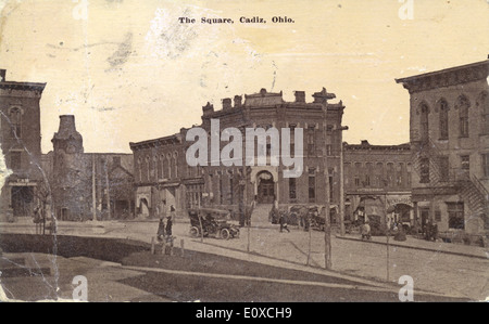 Diese Postkarte aus der Sammlung Bowden zeigt eine kommerzielle Straßenszene in Cadiz, Ohio. Das Bild zeigt den typischen amerikanischen Stadtplatz, der die Architektur aus der Mitte des 20. Jahrhunderts und das geschäftige Geschäft eines kleinen Einkaufsviertels in Ohio zeigt. Stockfoto