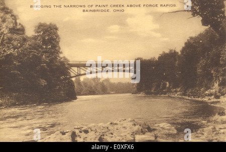 Diese Postkarte aus der Bowden-Kollektion zeigt die ikonische Brücke über den Paint Creek in Bainbridge, Ohio, mit Forge Rapids im Hintergrund. Das Bild fängt die ruhige Schönheit und das technische Wunderwerk der Brücke ein. Stockfoto