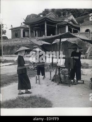 1. Januar 1970 - vom frühen Morgen bis zum Sonnenuntergang werden chinesische Mädchen an primitiven Apparaten auf offenen Standorten in Aau mit Schnur verdreht. Sie laufen vorwärts und rückwärts und führen die Garnlängen. Da sie von einem Wannenrad aufgewickelt werden, werden sie zu Kugeln aus farbigem, verdrehtem Garn für die Paketwicklung zusammengefügt. Stockfoto