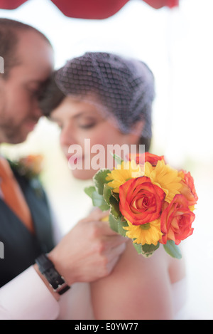 Braut und Bräutigam im Hintergrund mit Blumenstrauß auf dem display Stockfoto