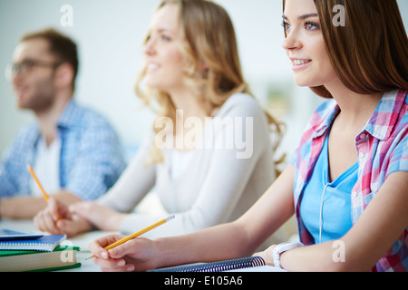 Intelligentes Mädchen hören Lehrer am Seminar mit ihren Kollegen auf Hintergrund Stockfoto