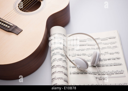 ein Kopf auf einem Notizbuch neben einer akustischen Gitarre gesetzt Stockfoto