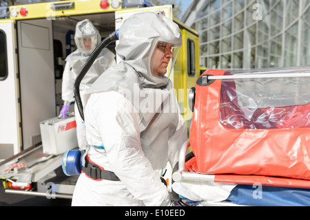 Biohazard-medizinische Team-Mitglied mit Bahre im Freien mit einem Krankenwagen Stockfoto