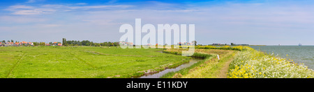 Ein Deich durch typische holländische Landschaft an einem hellen, sonnigen Tag im Frühling Stockfoto