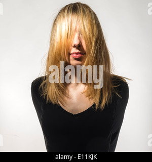 Eine junge blonde Frau Mädchen tragen schwarze Kleidung mit ihrer Haare, die ihr Gesicht versteckt Stockfoto