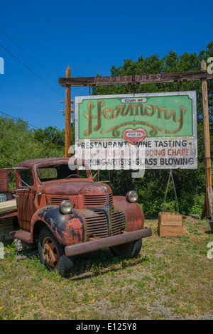 Eine verrostete, vernachlässigten alten Dodge Truck sitzt vor einem verblichenen Plakatwerbung der kleinen Stadt der Harmonie, California. Stockfoto