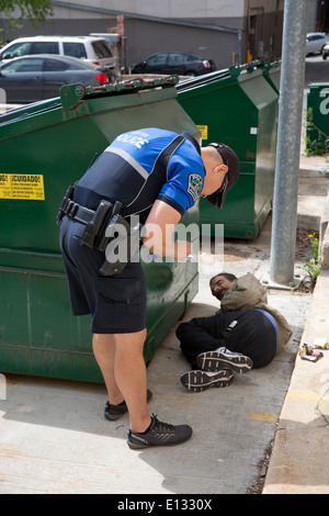 Polizist Fragen Obdachlosen Mann, der hinter geschlafen hatte Müllcontainer in der Innenstadt von Austin Texas Stockfoto