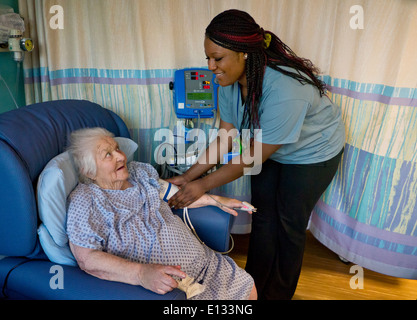 Krankenschwester und ältere ältere Dame in NHS Krankenhaus Station mit Ihr Blutdruck nahm attraktive lächelnde Pflege Krankenhaus Krankenschwester Stockfoto