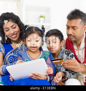 Indische asiatischen Familie mit digital-Tablette pc Computer online-shopping mit Kreditkarte zu Hause. Indien leben Lebensstil. Glücklich lächelnden Eltern und Kinder. Stockfoto