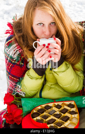 Junges Paar beim Picknick am Valentinstag in einem verschneiten Park. Stockfoto