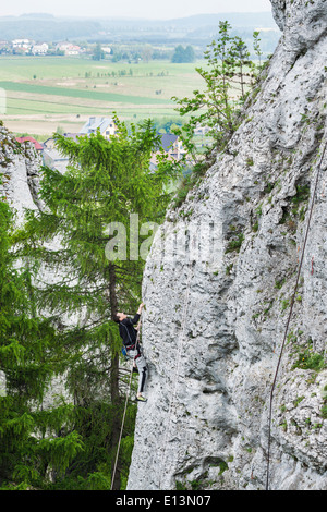 Mann, die steilen und hohen Felswand klettern. Stockfoto