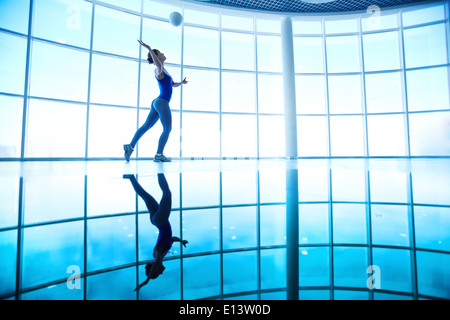 Junge Frau spielt mit Ball im Fitness-Studio im Hintergrund des Fensters Stockfoto