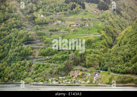 Norwegen, Geiranger, Geiranger Fjord. UNESCO-Weltkulturerbe. Blick auf Dorf und die Adler-Straße mit 11 Haarnadelkurven. Stockfoto