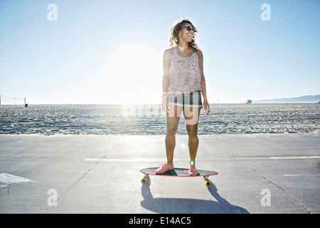 Afroamerikanische Frau Longboard am Strand Reiten Stockfoto