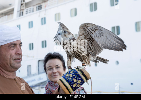 Vereinigte Arabische Emirate, Abu Dhabi, Falconer und Touristen, Frau, mit Falken vor Kreuzfahrtschiff Stockfoto