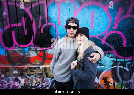 Kaukasische Mutter und Sohn umarmt von Graffitiwand Stockfoto