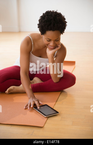 Schwarze Frau mit digital-Tablette auf Yoga-Matte Stockfoto