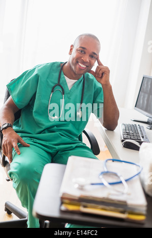 Schwarzen Doktor lächelnd am Computer im Büro Stockfoto