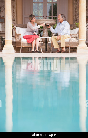 Paar, toasten einander Swimming Pool Stockfoto