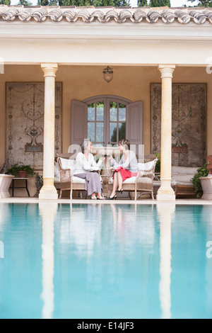 Frauen, die einander Swimmingpool Toasten Stockfoto