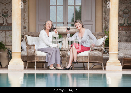 Frauen, die einander Swimmingpool Toasten Stockfoto