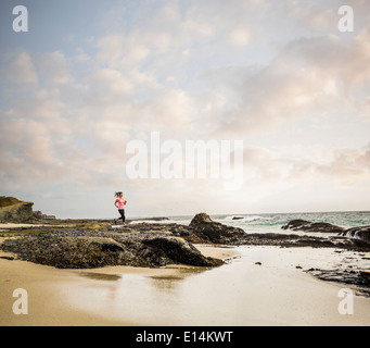 Kaukasische Frau läuft am Strand Stockfoto