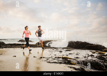 Kaukasische paar laufen am Strand Stockfoto