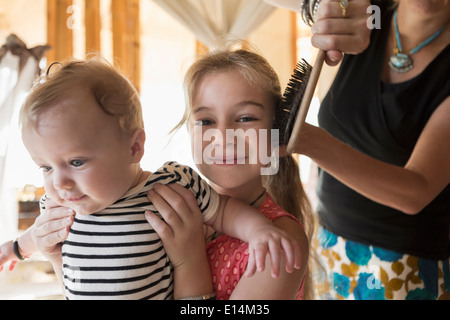 Kaukasische Mädchen Holding Bruder als Mutter ihr Haar Bürsten Stockfoto