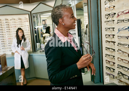 Schwarze Frau, die versucht auf Gläser beim Optiker Stockfoto