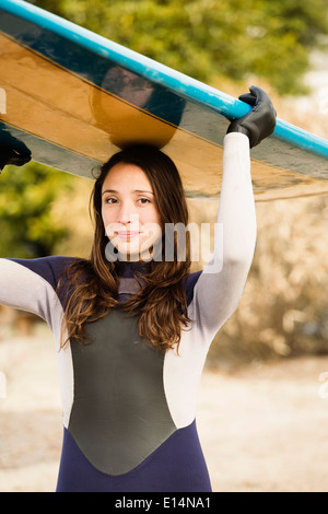 Hispanische Surfer tragen Board am Strand Stockfoto